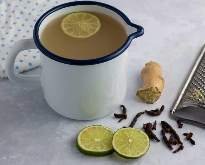 Lamugine | Spicy West African Ginger Drink in a cup with a slice of lime
