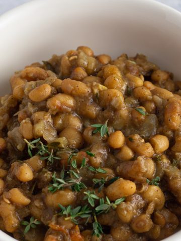 Caribbean curried beans with fresh thyme garnish in a bowl