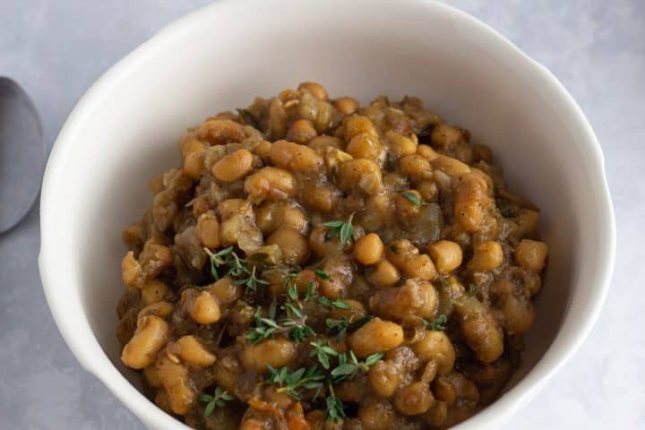 Caribbean curried beans with fresh thyme garnish in a bowl