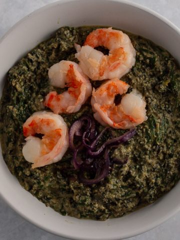 Ndole (Cameroonian bitter leaf stew) with prawn and onion toppings in a white bowl.