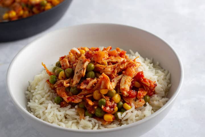 Peri peri shredded chicken with vegetables served on a bed of rice.