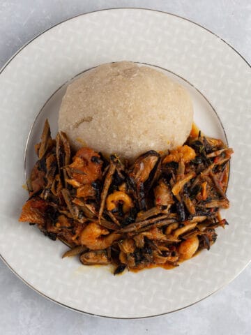 Ugba/Ukpaka (African oil bean seed) sauce with smoked turkey, seafood and kale served with eba