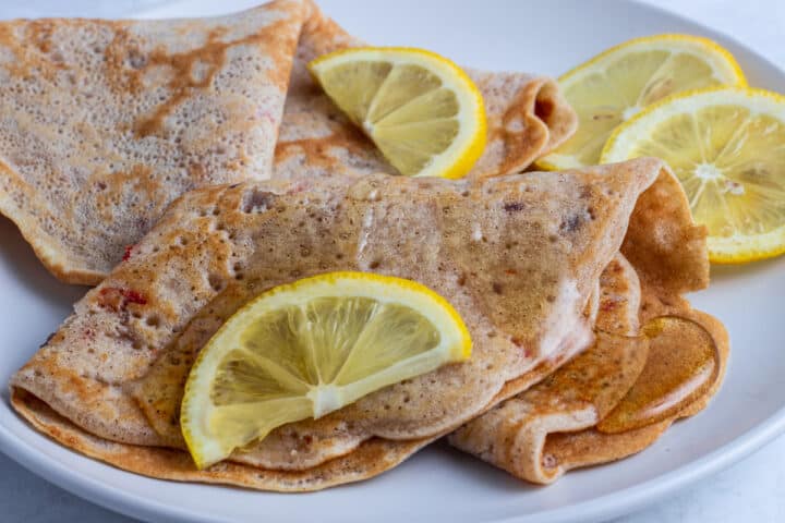 Nigerian style pancakes with lemon and honey drizzle on a white plate
