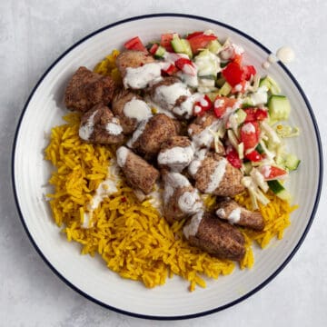 Chicken shawarma - Yellow rice, chicken shawarma and salad with garlic in a bowl