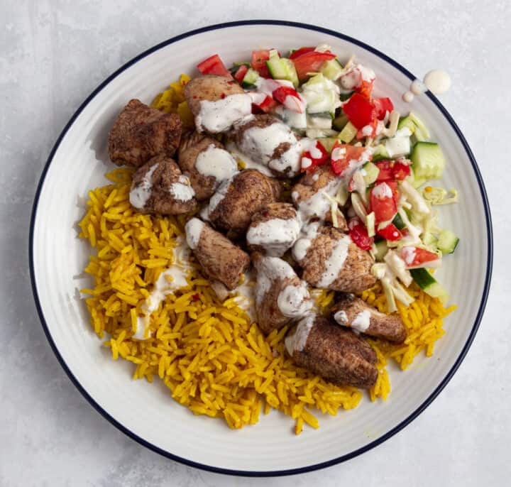 Chicken shawarma - Yellow rice, chicken shawarma and salad with garlic in a bowl
