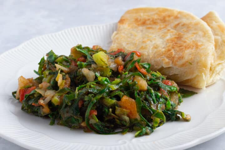 East African Braised Collard Greens - Sukuma Wiki. Served with Chapati on a white plate